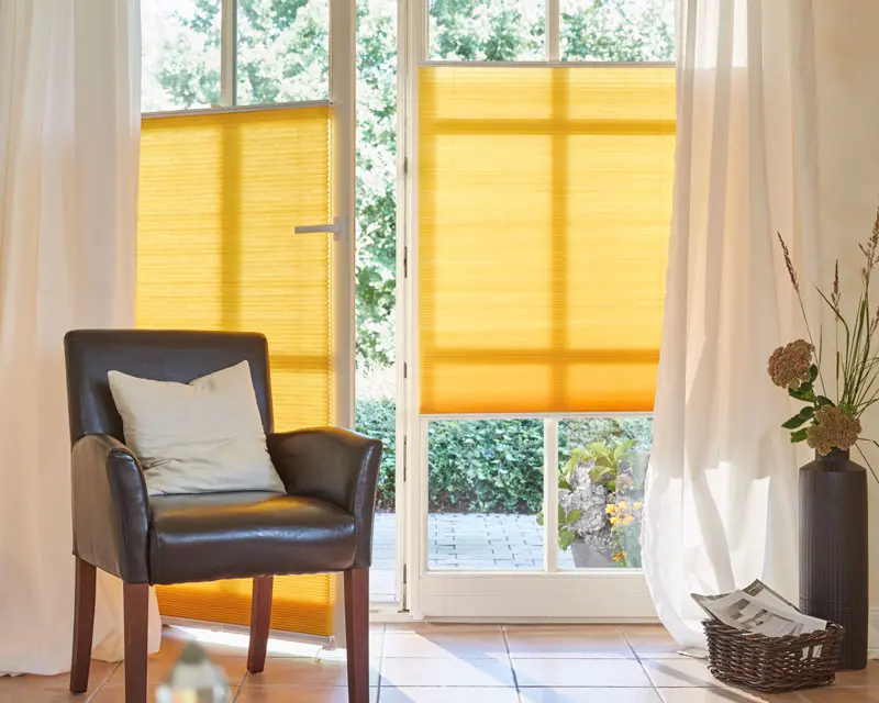 Gelbe Plissees an einer offenen Terassentür in einen Wohnzimmer