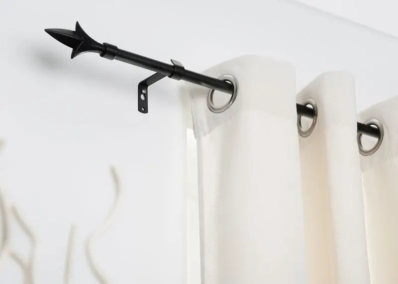 Gardinenstange in schwarzen Edelstahl mit Bohrung angebracht an eine weiße Wand mit weißer Gardine und Pfeilabschluss
