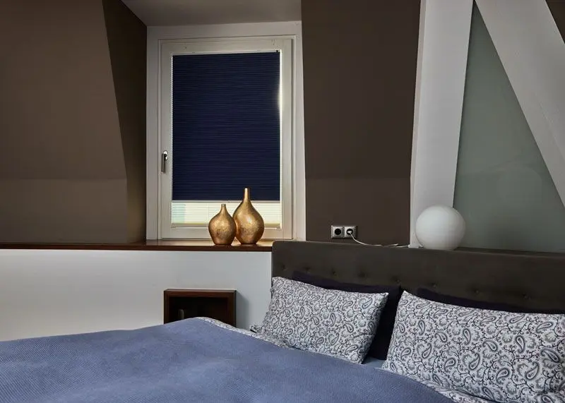 Verdunkelungsplissee in blau angebracht in einem Schlafzimmerfenster