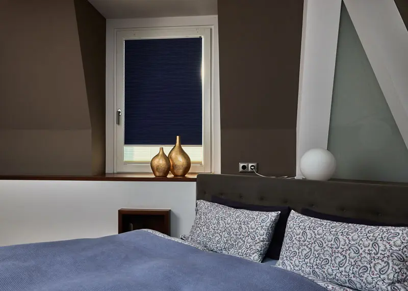 Wabenplissee mit Verdunklungsfunktion in blau angebracht in einen Schlafzimmerfenster