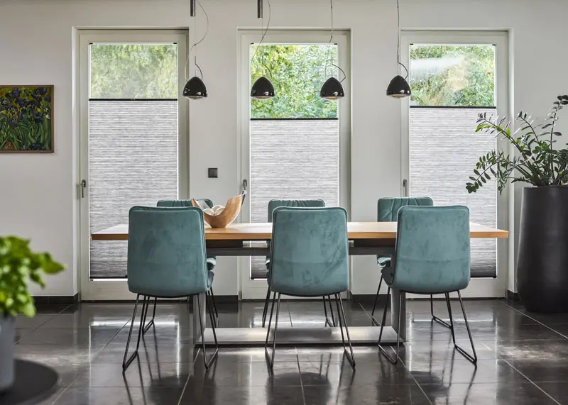 Blickdichtes Wabenplissee in grau angebracht in bodentiefen Fenstern in einem Esszimmer