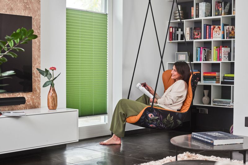 Plissee mit Sonnenschutz in Grün angebracht in einen Wohnzimmerfenster Plissee mit Sonnenschutz in Grün angebracht in einen Wohnzimmerfenster