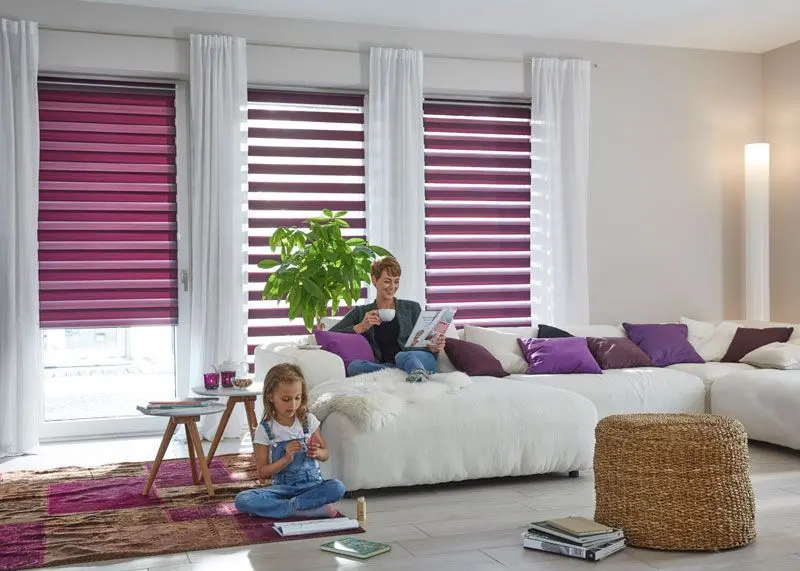 Doppelrollo für das Wohnzimmer in Rosa und Lila als blickdichter Sichtschutz angebracht in bodentiefen Fenstern