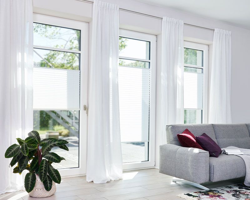 Plissees für alle Räume in einer Terrassentür in einem Wohnzimmer Plissees für alle Räume in einer Terrassentür in einem Wohnzimmer