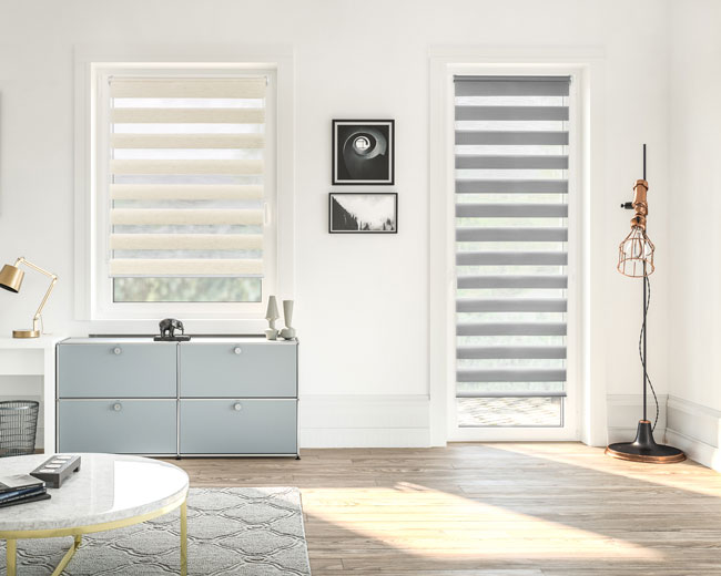 Doppelrollos für Fenster und Türen in Grau und Weiß angebracht in einem Wohnzimmer
