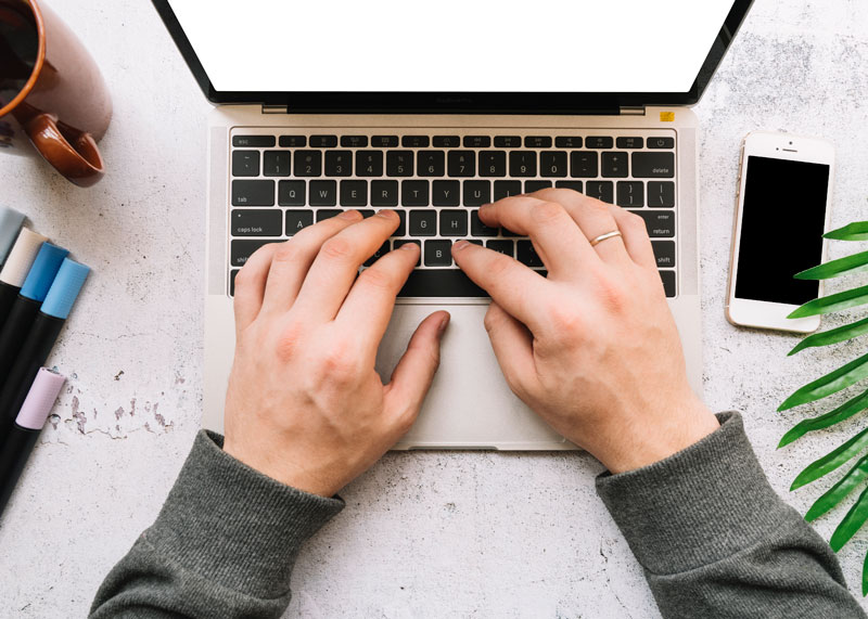 Aufgeklappter Laptop auf einen Tisch mit Handy sowie Stiften und einer Tasse Aufgeklappter Laptop auf einen Tisch mit Handy sowie Stiften und einer Tasse