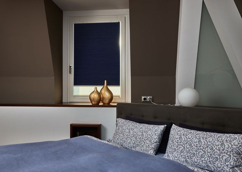 Verdunklungsplisse in Dunkelblau mit Thermofunktion in einem Schlafzimmerfenster